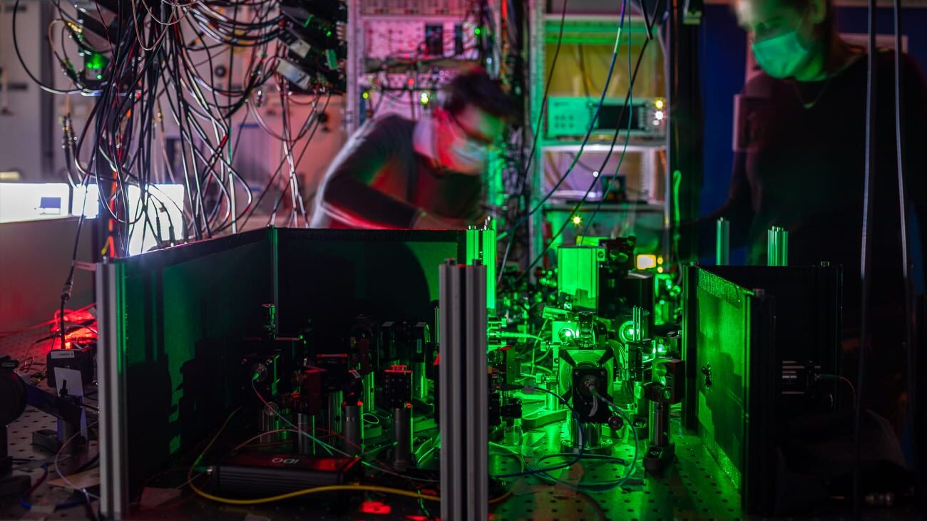 Onderzoekers werken aan een van de kwantumnetwerkknooppunten, waar spiegels en filters de laserstralen naar de diamantchip leiden. Krediet: Marieke de Lorijn voor QuTech.